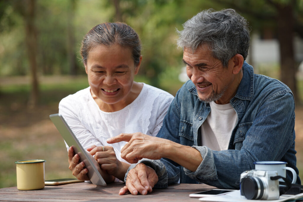 An older couple smiling together outdoors.