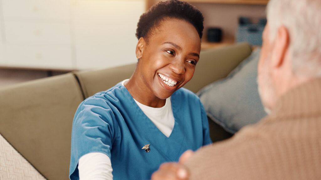 A smiling carer talking with an older person at home.