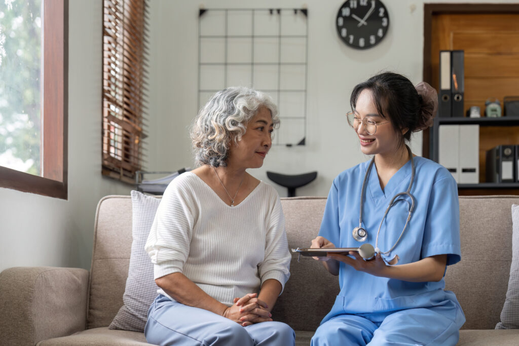 A carer sitting with an older woman during a home visit.