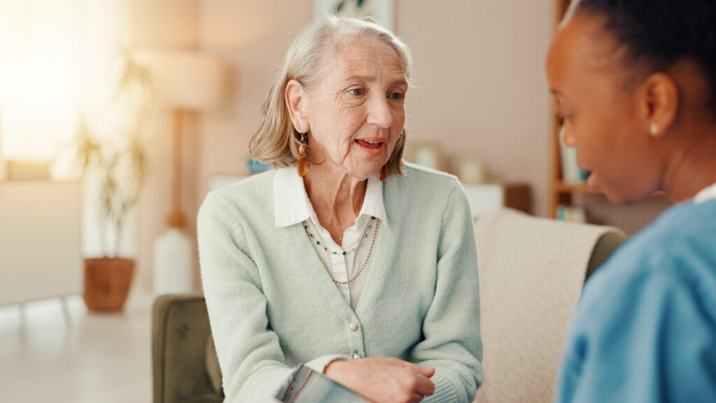 An older woman and a carer enjoying a conversation at home.