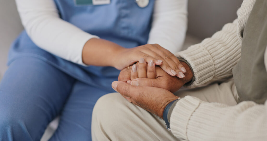 A reassuring hand held during a care visit.