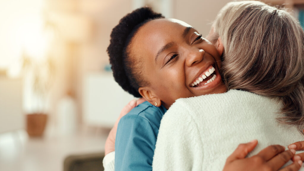 An older woman embracing a smiling carer.